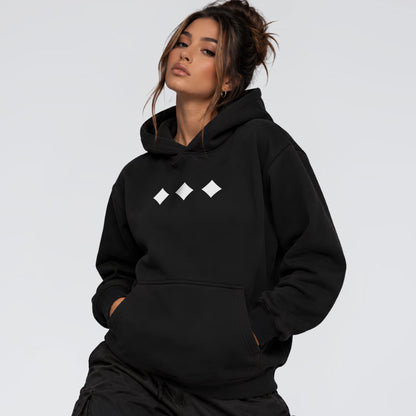 Female model wearing Raised Below black heavyweight hoodie with minimal white diamond chest graphics