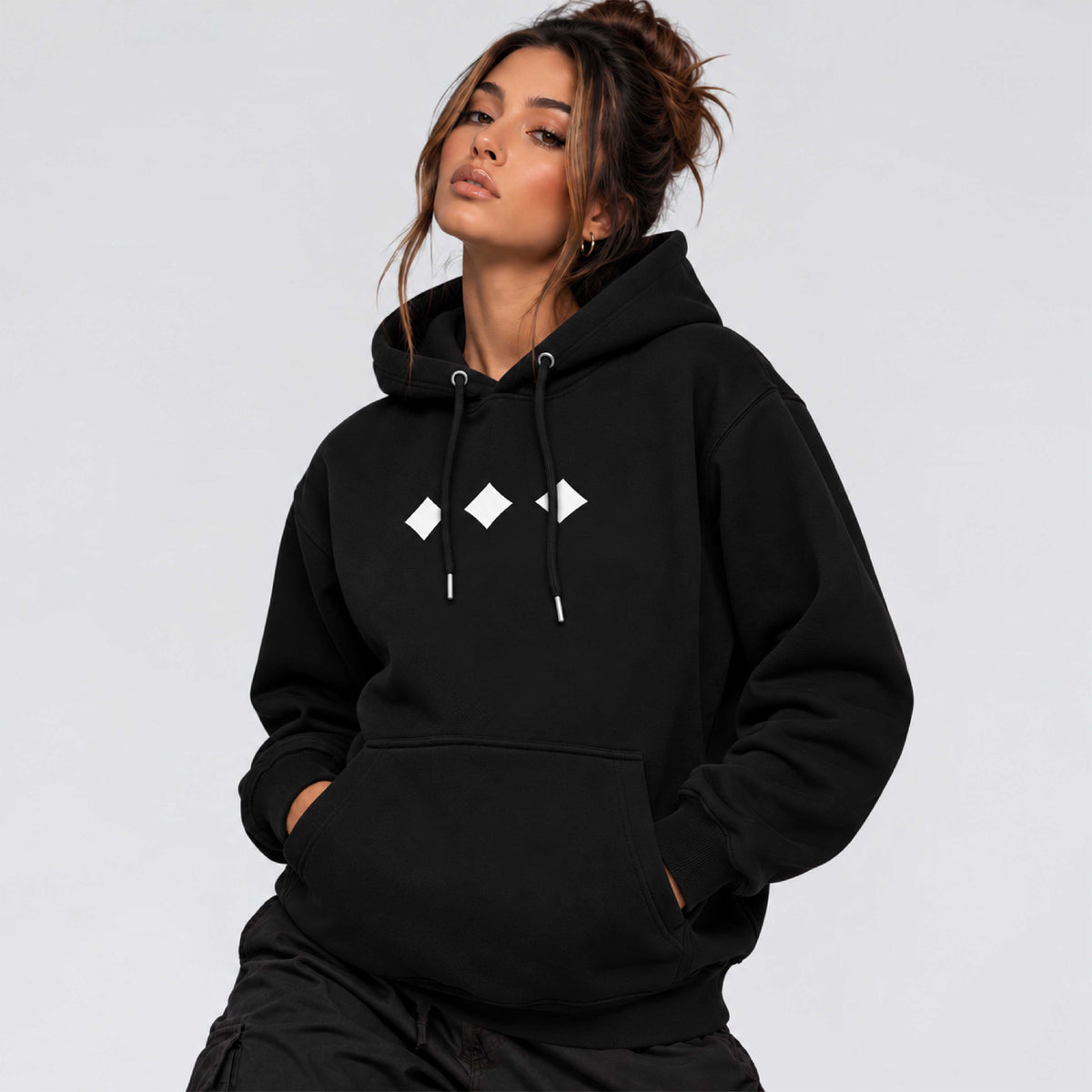 Female model wearing Raised Below black regular fit hoodie with minimal white diamond chest graphics