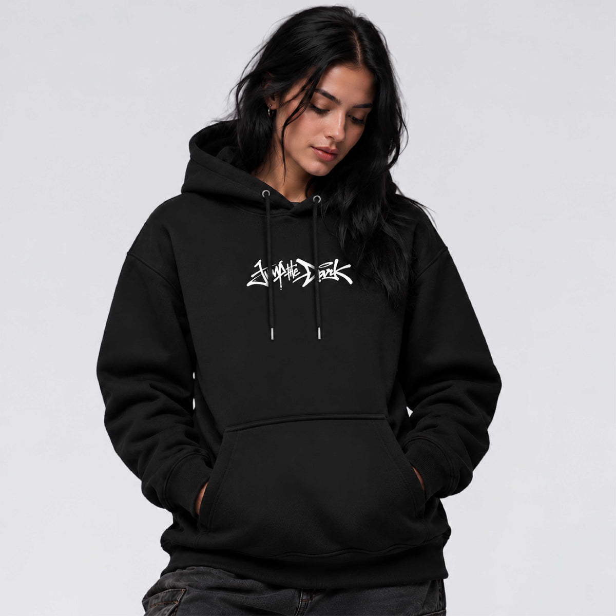 Female model wearing Signature black core streetwear hoodie with Jump the Dark chest logo